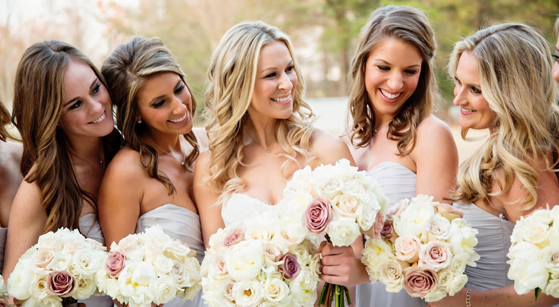 A bridal party giggles with their bouquets