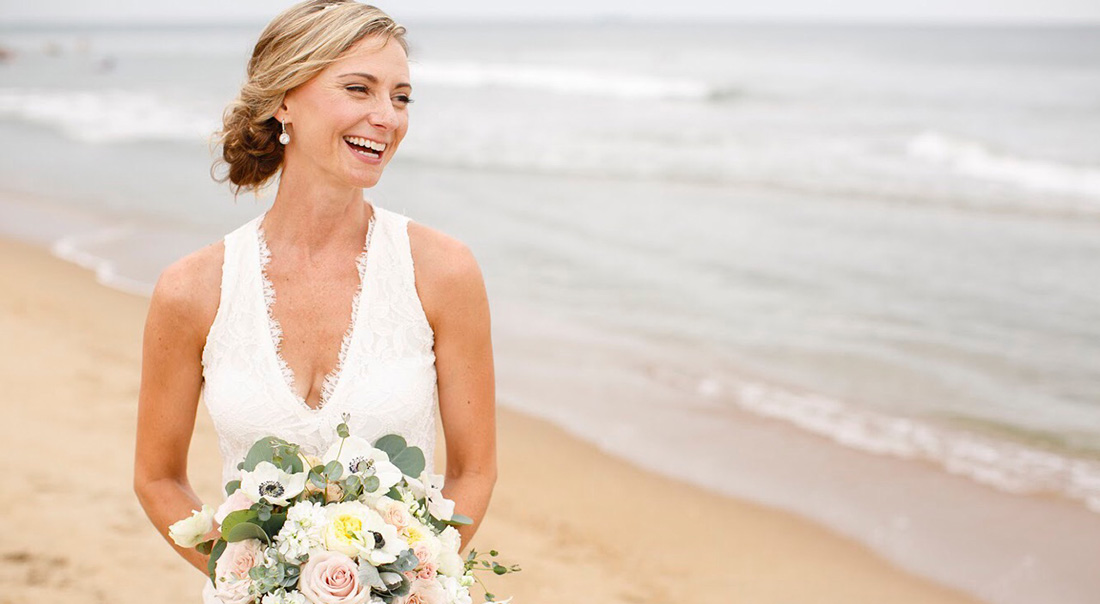A beachy bride laughs in the surf